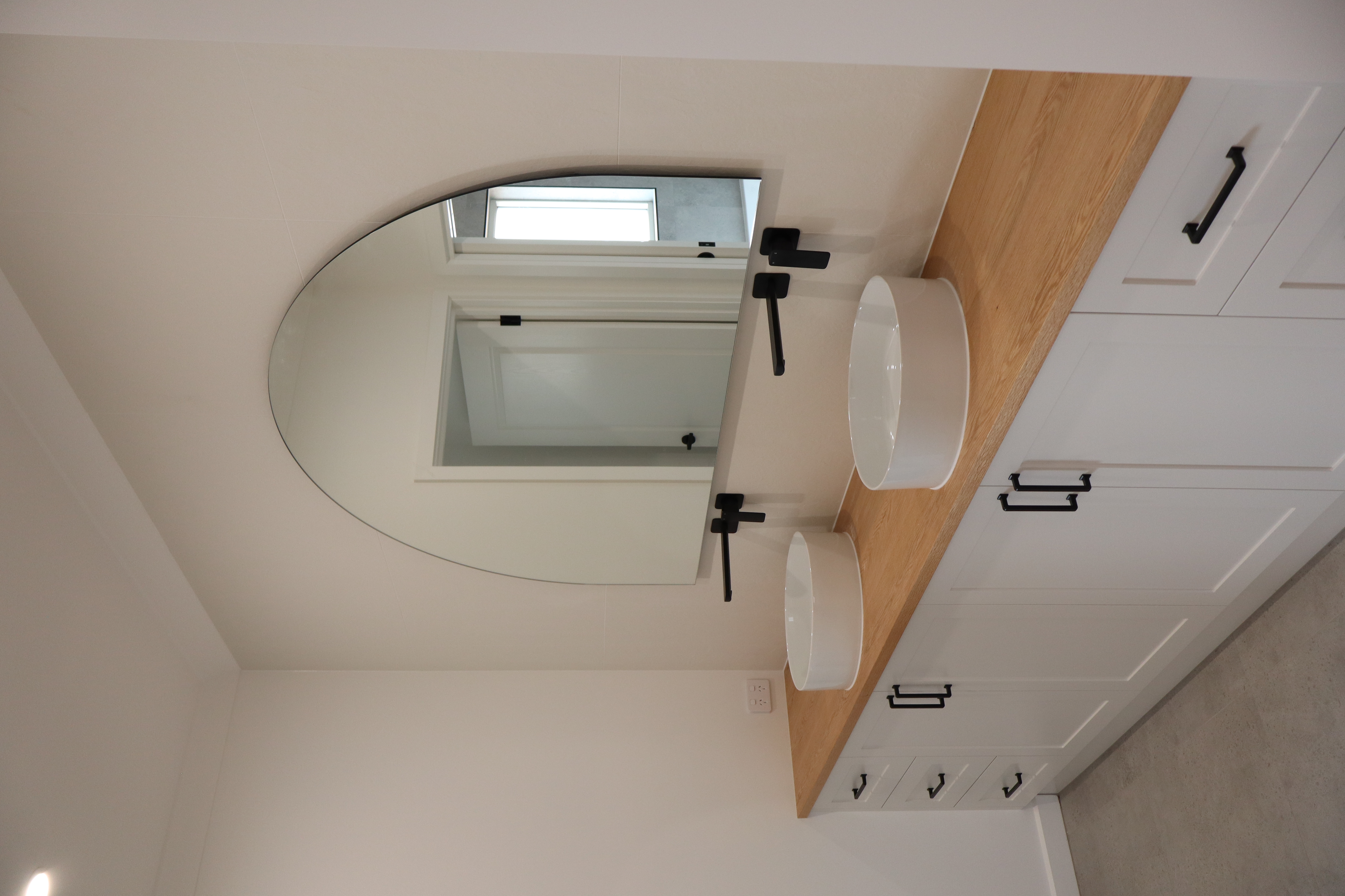 Modern new build bathroom with double vessel sinks, timber benchtop, and matte black fixtures