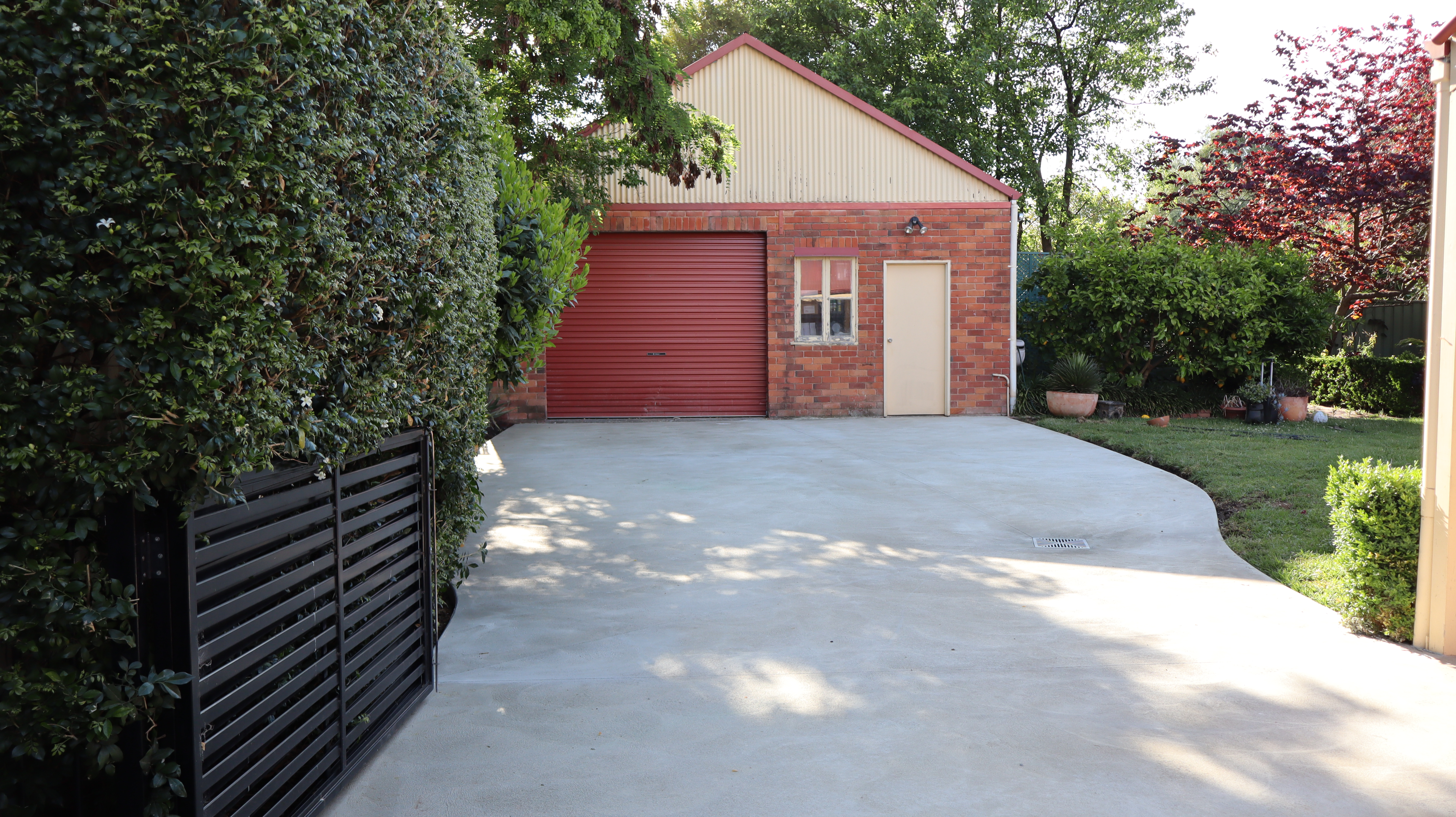 Modern concrete driveway with smooth finish leading to brick garage
