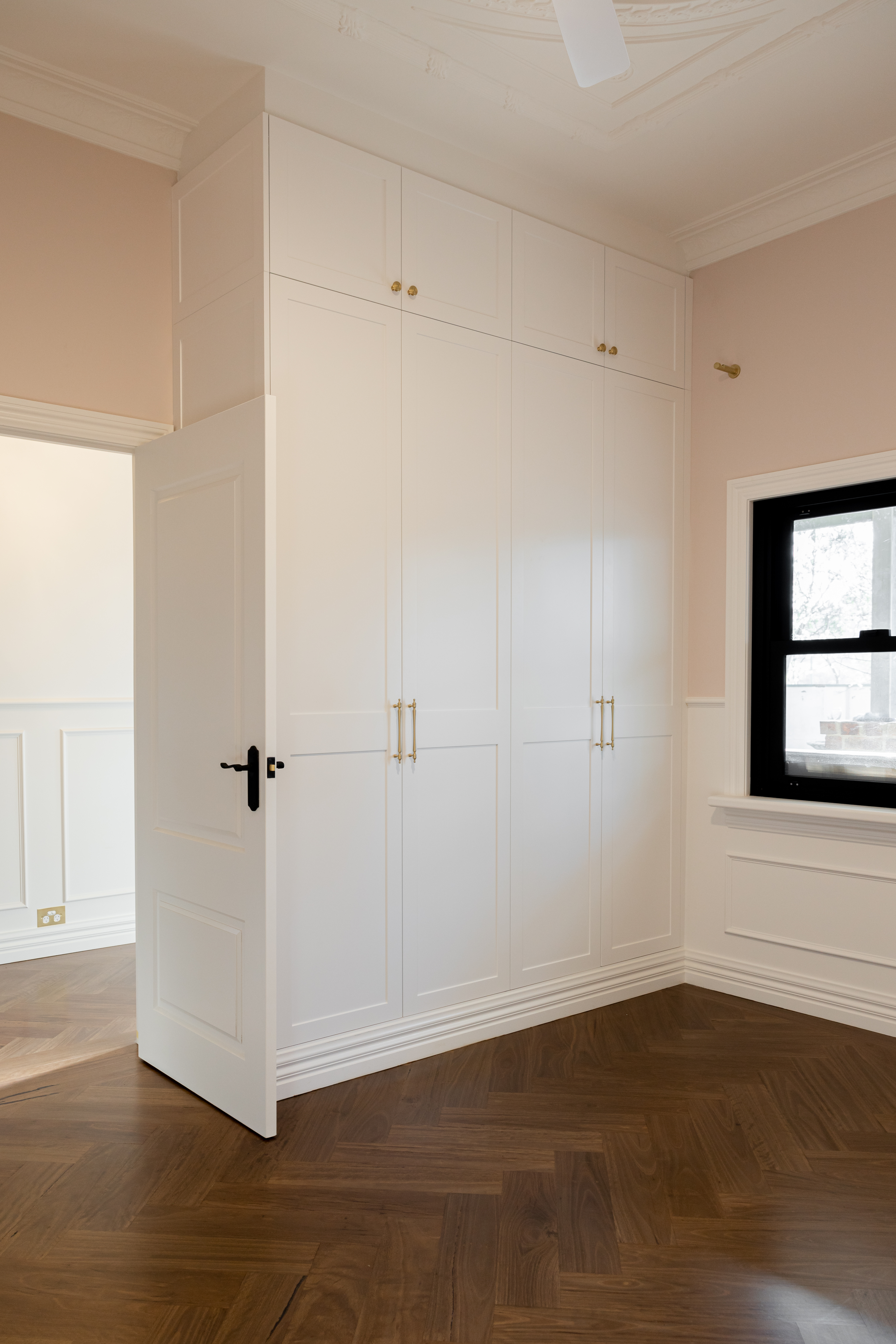 Custom built-in wardrobes with herringbone timber floors and heritage ceiling details