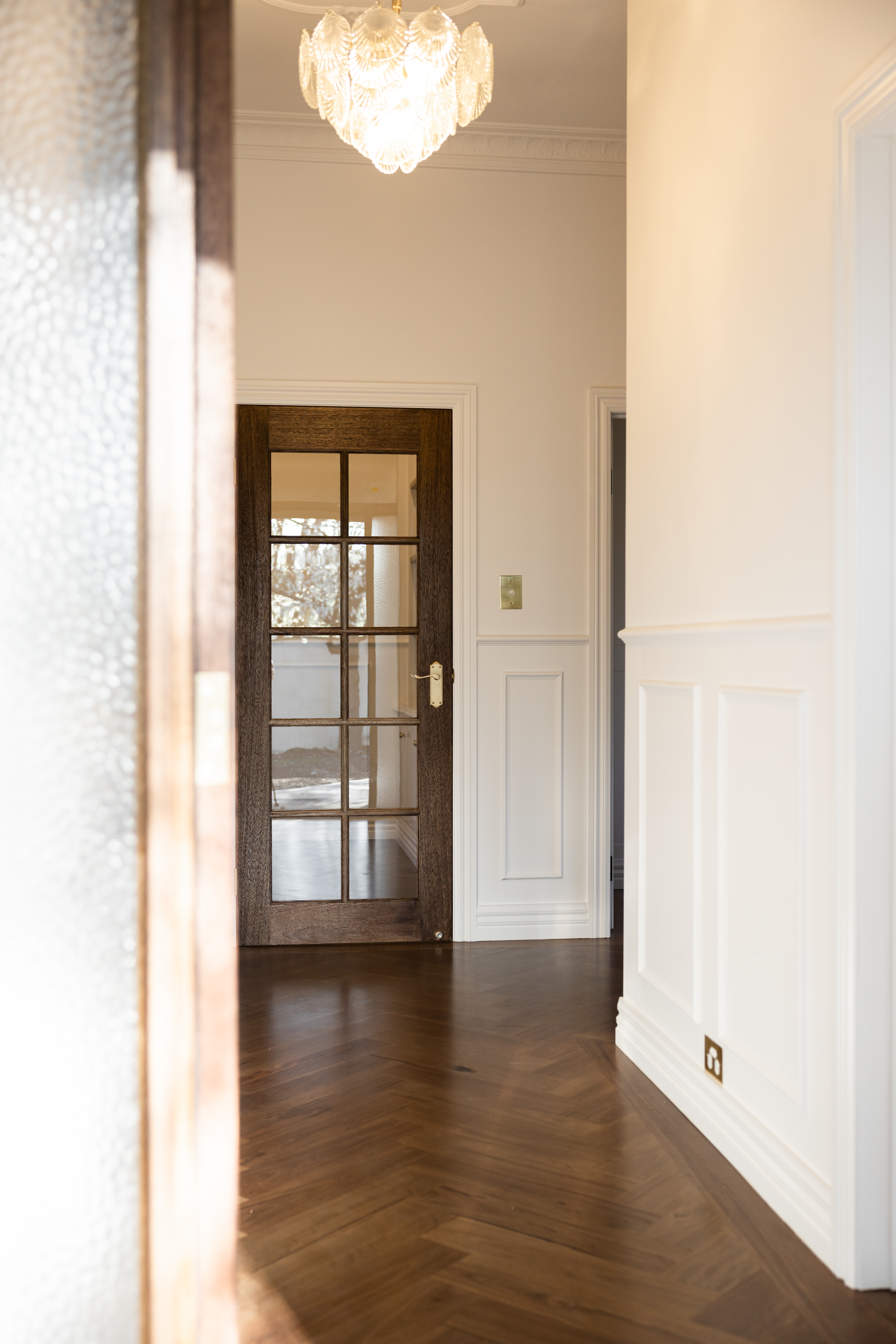 Hallway with vintage glass chandelier, timber doors and herringbone flooring