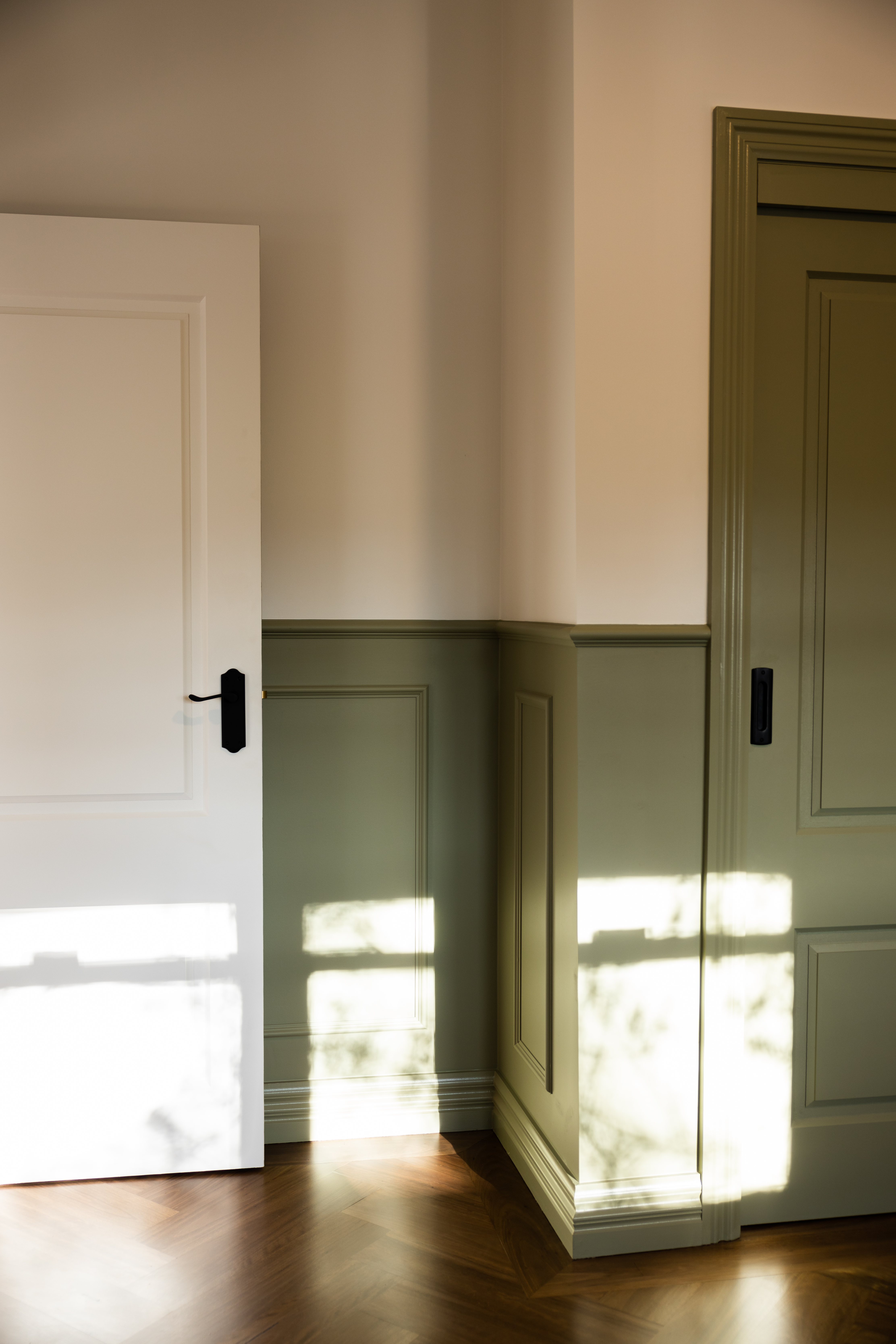 Sage green wainscoting with herringbone floors and natural light